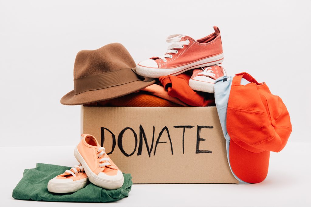 cardboard box with donated accessories, clothes and footwear isolated on white, charity concept