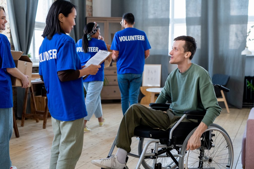 Young female volunteer standing in front of man in a wheelchair